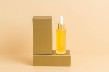 Sarı damlalık serum şişesi ya da altın podyumda duran bej arkaplanlı yağ. C vitamini ile organik cilt bakımı kozmetikleri, sağlık, kaplıca ve güzellik tedavi konsepti, ürün modeli