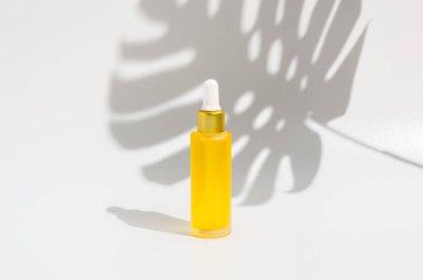 Göz damlası şişesi sarı serum ya da tropikal canavar gölgesi olan beyaz arka planda gerekli yağ. Organik cilt bakım ürünleri. Sağlık, kaplıca ve güzellik konsepti. Ürün modeli.