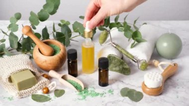 Kadın, pipet damlasıyla cilt bakımı yağı döküyor. Doğal aromaterapi okaliptüs gerekli yağlar ve banyo tuzlarıyla. Sıfır atık spa ve sağlık ürünleri. Çevre dostu banyo aksesuarları.
