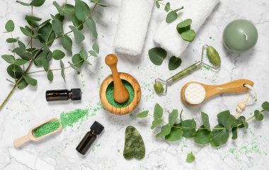 Doğal cilt bakımı ve okaliptüslü aromaterapi gerekli yağ şişeleri, banyo tuzu, güzellik yeşimi silindiri, mermer arka planda gua sha. Spa, sağlık, masaj ve rahatlama konsepti. Üst manzara, düz uzanma