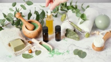 Cilt bakım yağı ya da serum damlatan kadın eli. Spa, sağlık ve güzellik ürünleri, gua sha, yüz silindiri. Ökaliptüs esaslı yağlar ve banyo tuzlarıyla doğal aromaterapi.