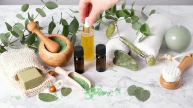 Cilt bakım yağı ya da serum damlatan kadın eli. Spa, sağlık ve güzellik ürünleri, gua sha, yüz silindiri. Ökaliptüs esaslı yağlar ve banyo tuzlarıyla doğal aromaterapi.