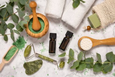 Doğal cilt bakımı ve okaliptüslü aromaterapi gerekli yağ şişeleri, banyo tuzu, güzellik yeşimi silindiri, mermer arka planda gua sha. Spa, sağlık, masaj ve rahatlama konsepti. Üst manzara, düz uzanma