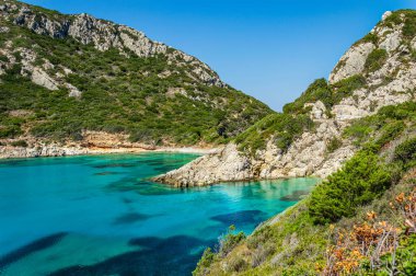 Yunanistan 'ın Korfu adasındaki Porto Timoni plajı. Yeşil dağların güzel manzarası, berrak deniz suyu tenha Pirates Körfezi ve gizli taşlı plaj. Yaz tatili ve yürüyüş için ünlü bir yer.