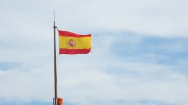 Mavi gökyüzüne ve beyaz bulutlara karşı rüzgarda dalgalanan İspanyol bayrağı. İspanya 'nın ulusal sembolü