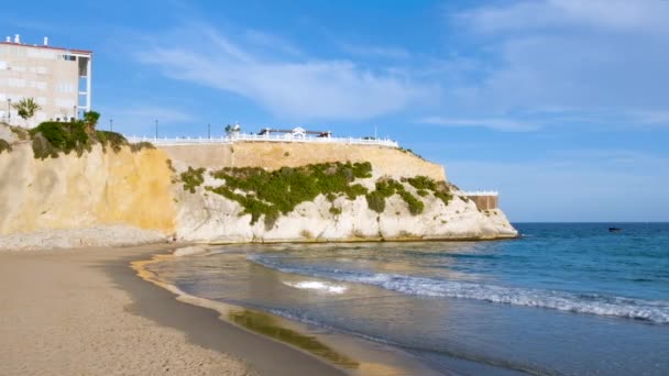 Ondas batendo contra a areia na praia de Mal Pas em Benidorm, Espanha. Pássaros voando sobre Mirador e varanda mediterrânea em penhasco na cidade velha. Região da Costa Blanca no mar Mediterrâneo — Vídeo de Stock