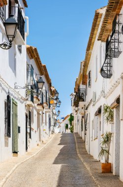 Typical view of Altea old town in Spain. Beautiful village with cobblestoned narrow streets, typical white houses and lanterns, popular tourist destination in Costa Blanca region. Vertical orientation clipart