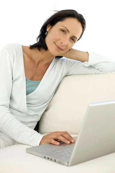 Женщина средних лет, использующая компьютер дома — стоковое фото
