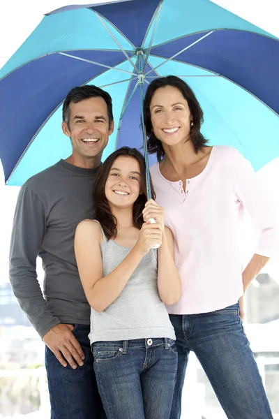 Familia feliz con un niño bajo un paraguas — Foto de Stock