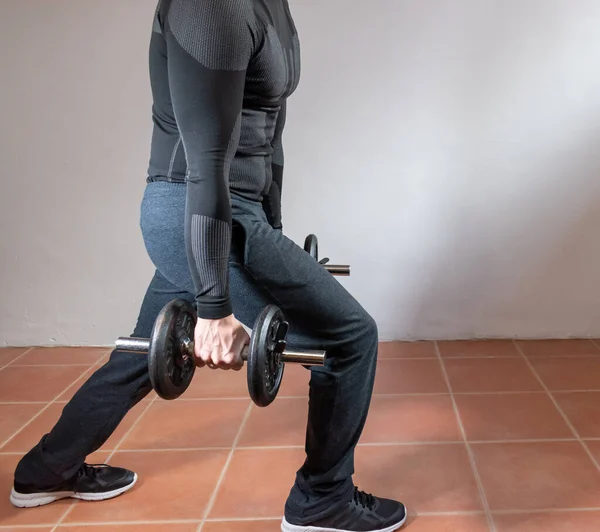 Adam evde uzun adımlı egzersizler yapıyor. Konsept: Evde fitness