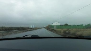 Yağmurda geleneksel bir yolda giden bir arabanın görüntüsü. Yağmurda araba kullanma kavramı