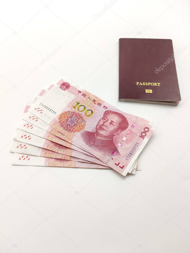 Stack of Chinese yuans banknotes and passport on a white background close up