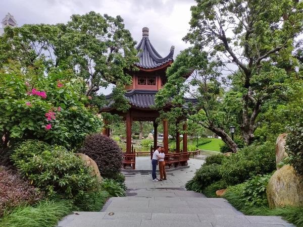 Néhány fel nem ismert férfi és nő a háttérben a kínai pagoda egy ázsiai stile park a fák között, kilátás messziről — Stock Fotó