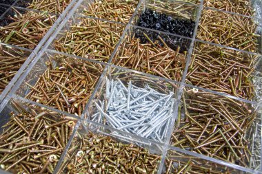 Çeşitli boyutlarda ve tiplerde bir yığın halinde düzenlenmiş bir sürü inşaat bağlayıcı, vida ve cıvata