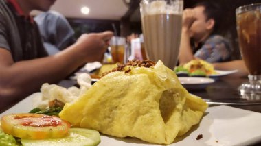 Omlete sarılı patates kızartması pilavı. Arka planda birlikte yemek yediğim arkadaşlarım var.