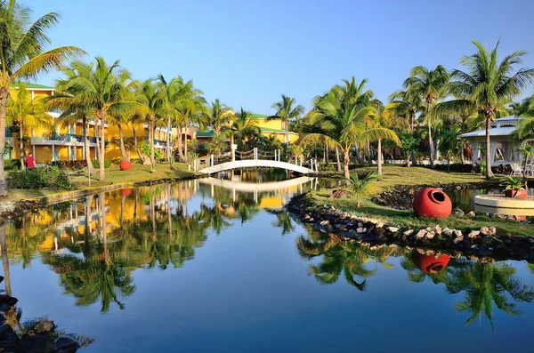 Bungalows mit Palmen, Fluss und Brücke - 2. — Stockfoto