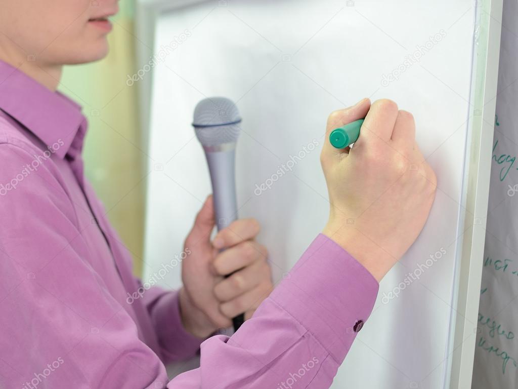 Person writing on flip chart desk.