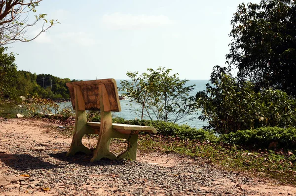 En tom bänk med utsikt över havet står på den höga stranden bland träden — Stockfoto