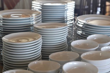 stacks of white porcelain plates and bowls on the table