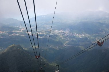 Teleferik kulübesinden dağ vadisine ve şehir alçak bulutların altında, üst manzara