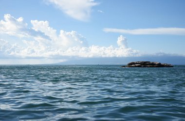 Küçük kayalık bir adası olan deniz burnu ufukta görünüyor.