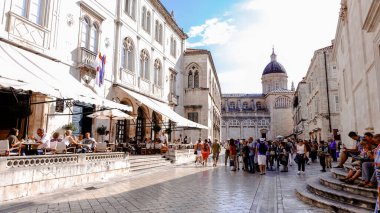 Dubrovnik 'in eski kasabasında hayat dolu bir manzara. Dubrovnik Katedrali manzaralı Dubrovnik eski şehrindeki kafede yürüyen ve oturan insanlar