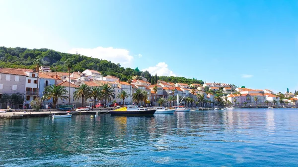 Korcula sahilinin panoramik manzarası. Limanda dağlar, evler ve tekneler var.