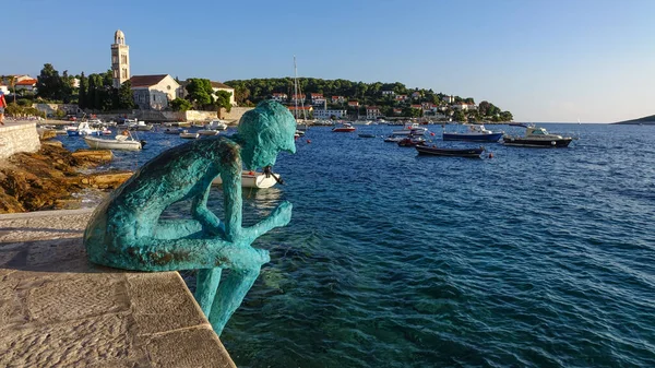 Old Town Hvar Limanı 'nda oturan balıkçı heykeli.