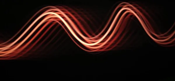 Neon red light curve wave pattern abstract flowing in a isolated Black background with copy space for texting Using Light painting technique