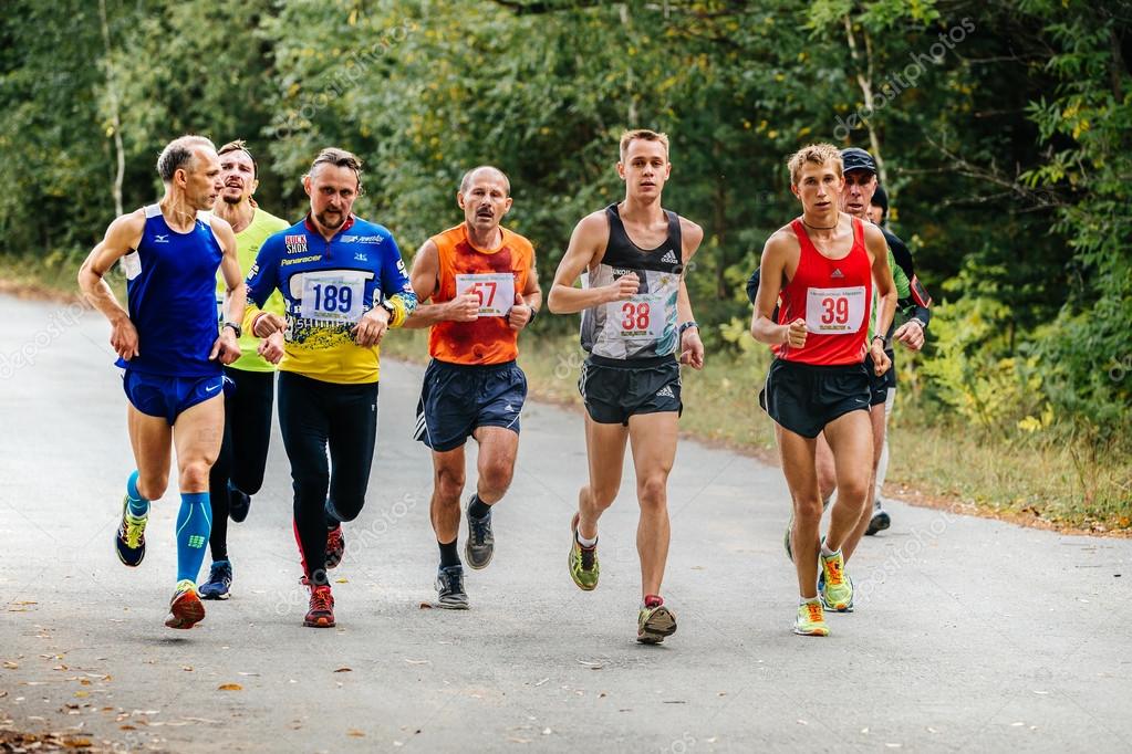 Large group of runners men middleaged and young run through Park