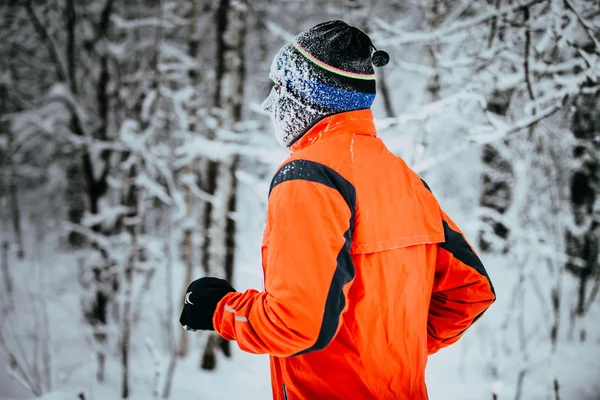 young male athlete running on winter alley in Park