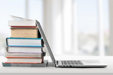 Dizüstü bilgisayar ile kitap yığını