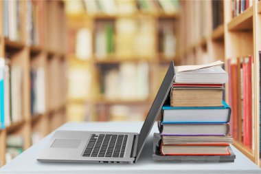 Dizüstü bilgisayar ile kitap yığını