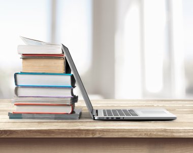 Dizüstü bilgisayar ile kitap yığını