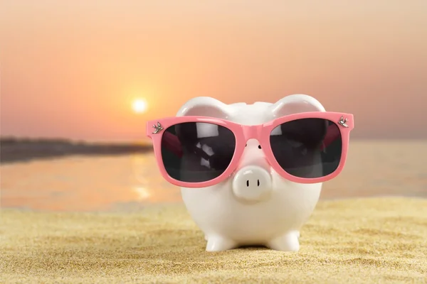 Piggy bank with sunglasses on the beach — Stock Photo, Image