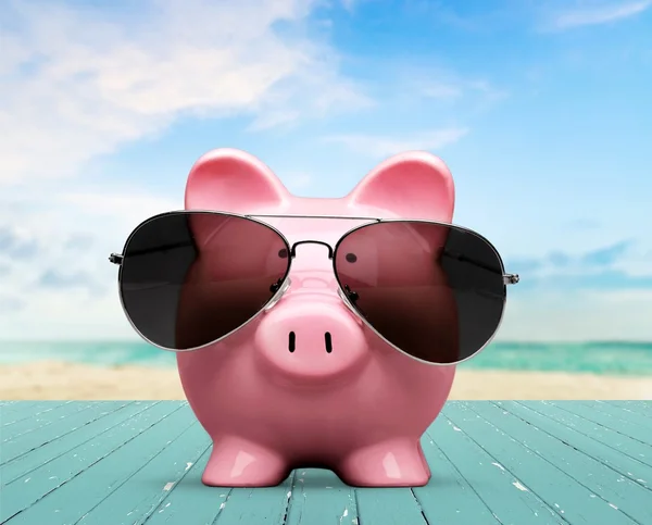 Piggy bank with sunglasses on the beach — Stock Photo, Image