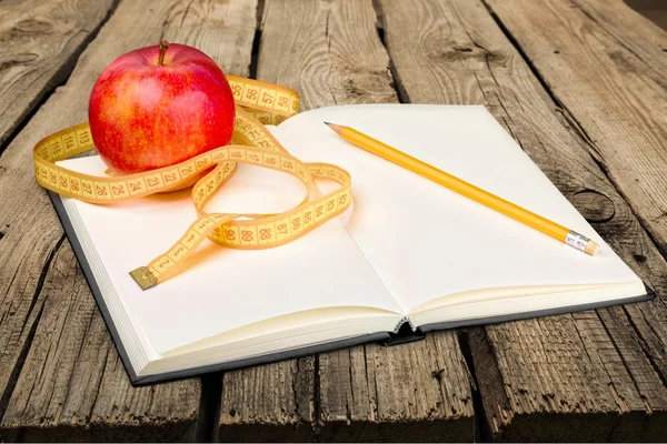 Notebook and pen with apple and measuring tape — Stock Photo, Image
