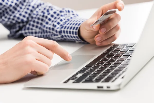 Hombre sosteniendo una tarjeta de crédito y escribiendo — Foto de Stock