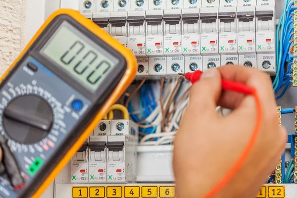 Hand av elektriker med multimetern sond — Stockfoto