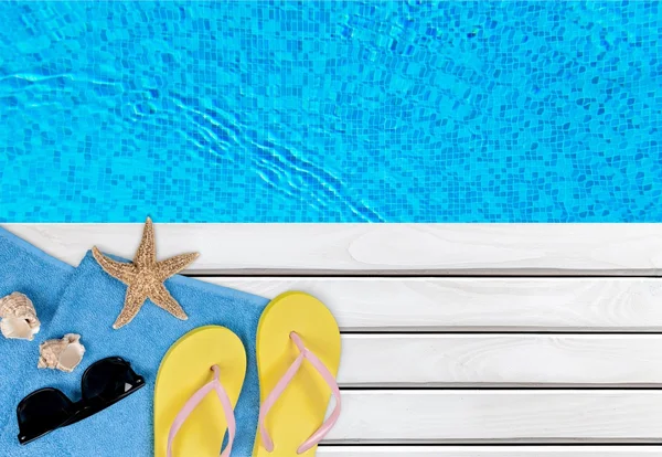 Chanclas y toalla junto a una piscina —  Fotos de Stock