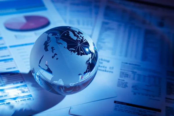 Glass globe with financial reports Royalty Free Stock Photos