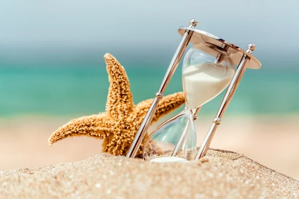 Hourglass and seastar on beach — Stock Photo, Image