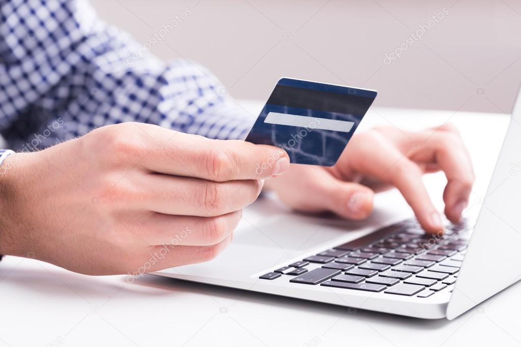 Man holding a credit card and typing