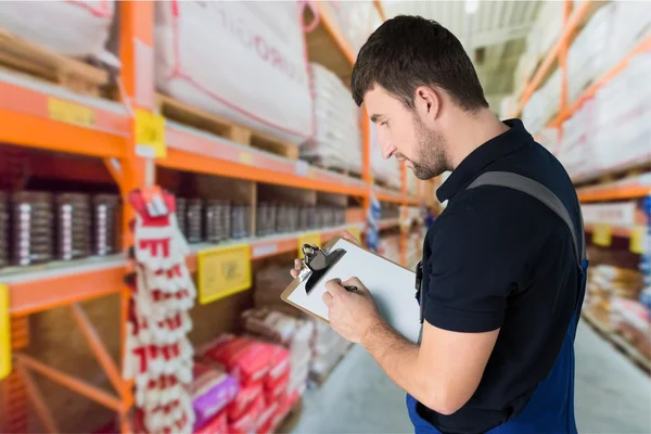 Levering man met Klembord in magazijn — Stockfoto