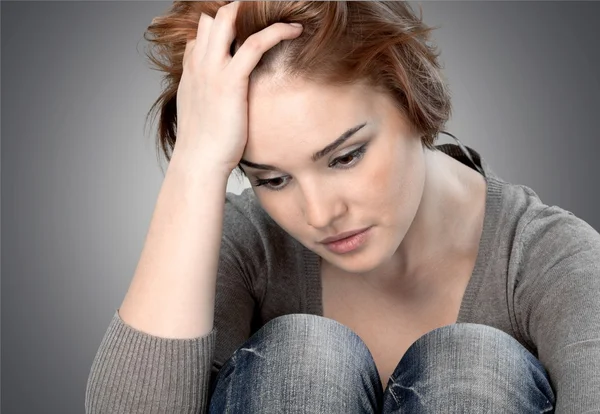 Worried woman sitting holding knees — Stock Photo, Image