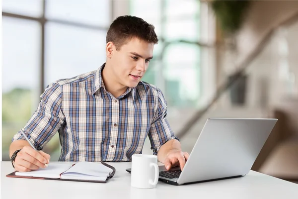 Счастливый молодой человек работает на своем ноутбуке — стоковое фото