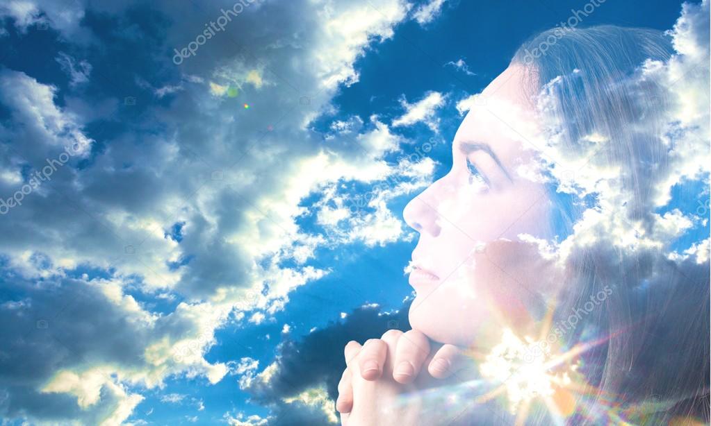 Woman praying over blue sky