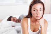 young woman in bed with sad expre