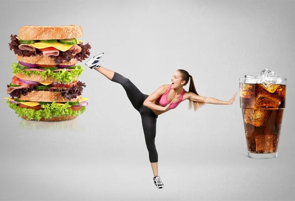 Mujer joven luchando contra la comida rápida — Foto de Stock