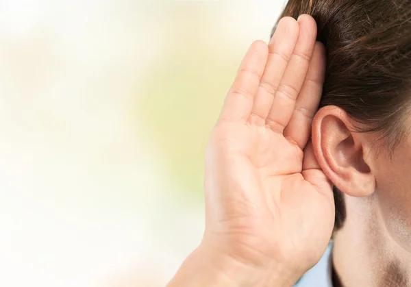 Businessman holds his hand near ear — Stock Photo, Image